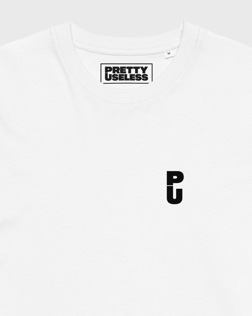 Detailansicht des kleinen schwarzen PU Logos auf der Brust eines weißen PRETTY USELESS T-Shirts.