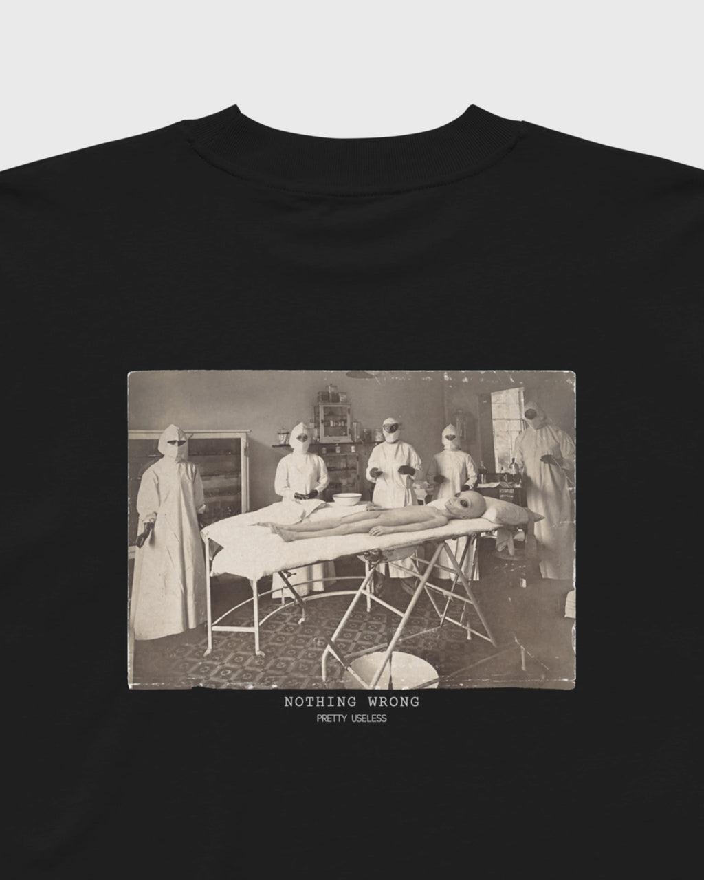 Detailansicht des NOTHING WRONG Prints mit surrealem Operationsmotiv auf einem schwarzen PRETTY USELESS Oversized T-Shirt.