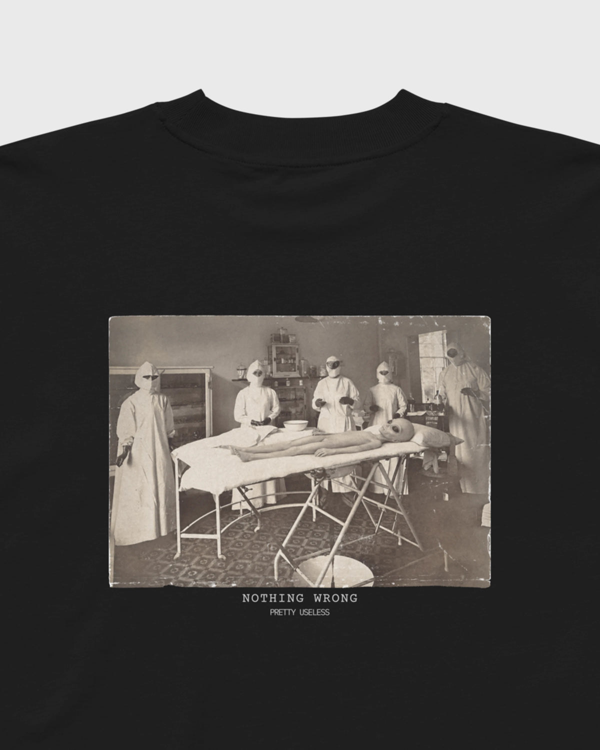 Detailansicht des NOTHING WRONG Prints mit surrealem Operationsmotiv auf einem schwarzen PRETTY USELESS Oversized T-Shirt.
