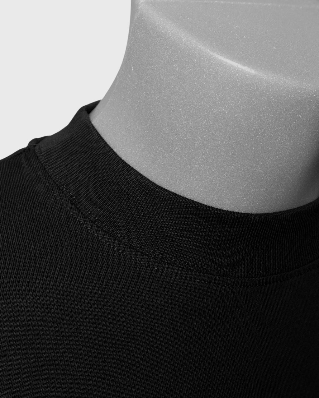 Detailaufnahme des gerippten Rundhalsausschnitts eines schwarzen PRETTY USELESS Oversized T-Shirts.