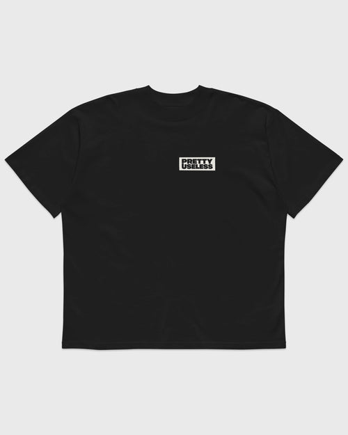 Frontansicht eines schwarzen PRETTY USELESS Oversized T-Shirts mit kleinem Logo-Print.