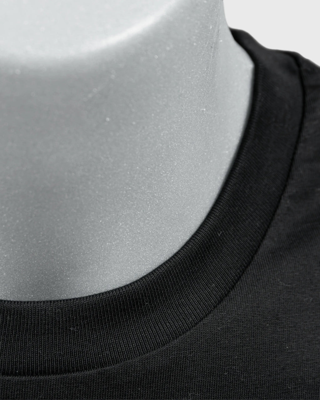 Detailaufnahme des schwarzen T-Shirt-Kragens mit geripptem Rundhalsausschnitt.
